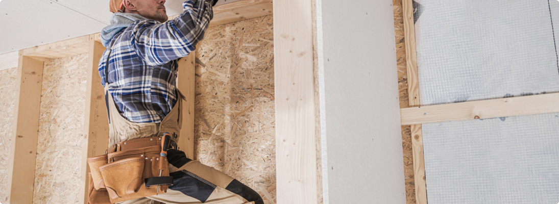 Construction worker assemble a suspended ceiling with drywall and fixing the drywall to the ceiling metal frame with screwdriver. Renovation, construction and ceiling installation concept.