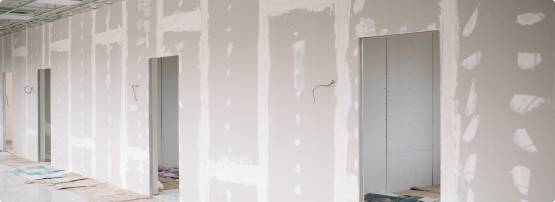 Construction worker assemble a suspended ceiling with drywall and fixing the drywall to the ceiling metal frame with screwdriver. Renovation, construction and ceiling installation concept.