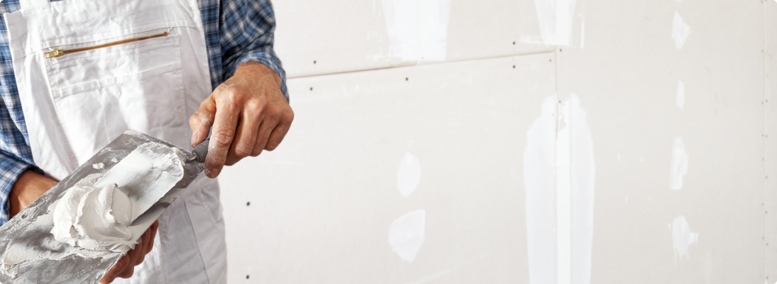 Construction worker assemble a suspended ceiling with drywall and fixing the drywall to the ceiling metal frame with screwdriver. Renovation, construction and ceiling installation concept.