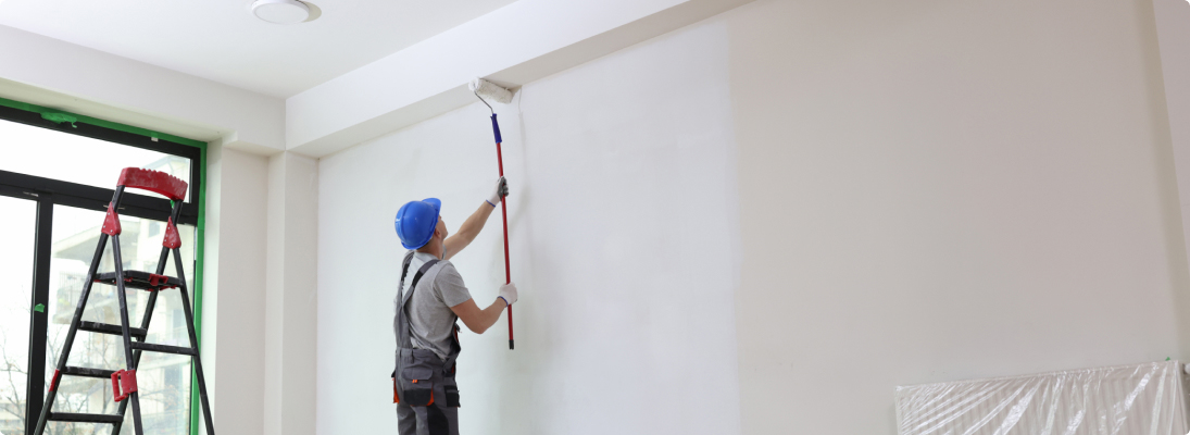 Construction worker assemble a suspended ceiling with drywall and fixing the drywall to the ceiling metal frame with screwdriver. Renovation, construction and ceiling installation concept.