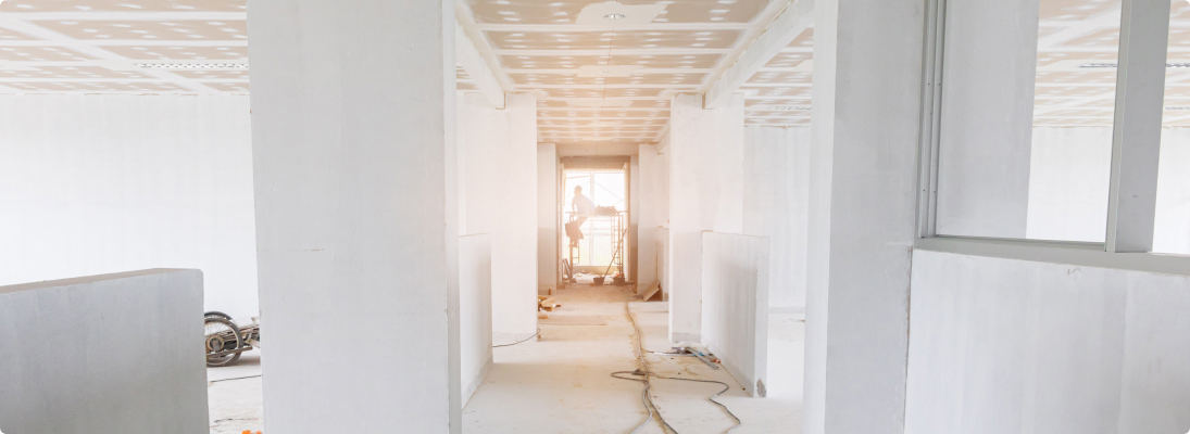 Construction worker assemble a suspended ceiling with drywall and fixing the drywall to the ceiling metal frame with screwdriver. Renovation, construction and ceiling installation concept.