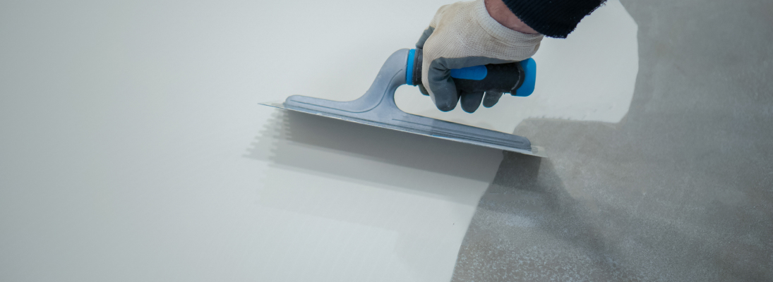 Construction worker assemble a suspended ceiling with drywall and fixing the drywall to the ceiling metal frame with screwdriver. Renovation, construction and ceiling installation concept.