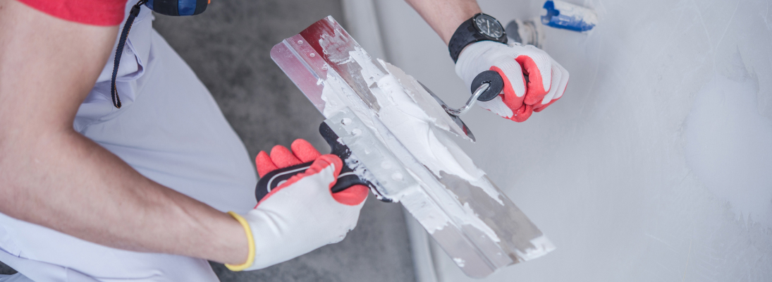 Construction worker assemble a suspended ceiling with drywall and fixing the drywall to the ceiling metal frame with screwdriver. Renovation, construction and ceiling installation concept.