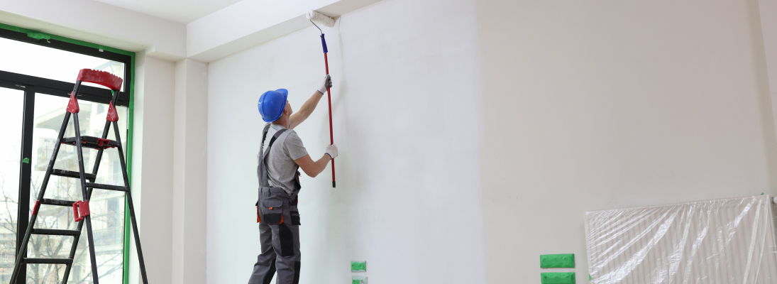 Construction worker assemble a suspended ceiling with drywall and fixing the drywall to the ceiling metal frame with screwdriver. Renovation, construction and ceiling installation concept.