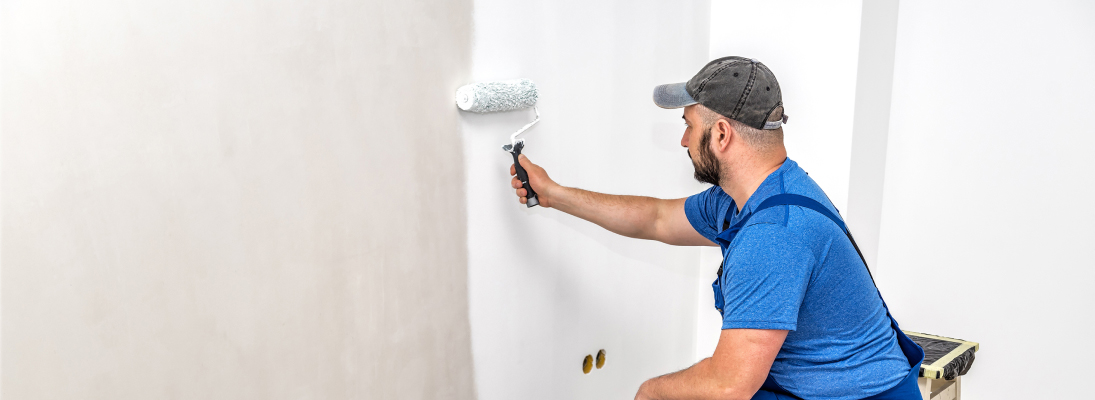 Construction worker assemble a suspended ceiling with drywall and fixing the drywall to the ceiling metal frame with screwdriver. Renovation, construction and ceiling installation concept.