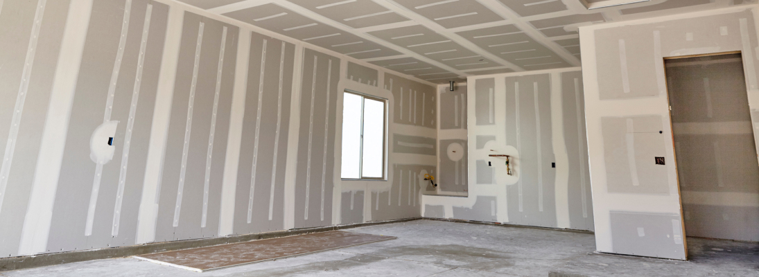 Construction worker assemble a suspended ceiling with drywall and fixing the drywall to the ceiling metal frame with screwdriver. Renovation, construction and ceiling installation concept.