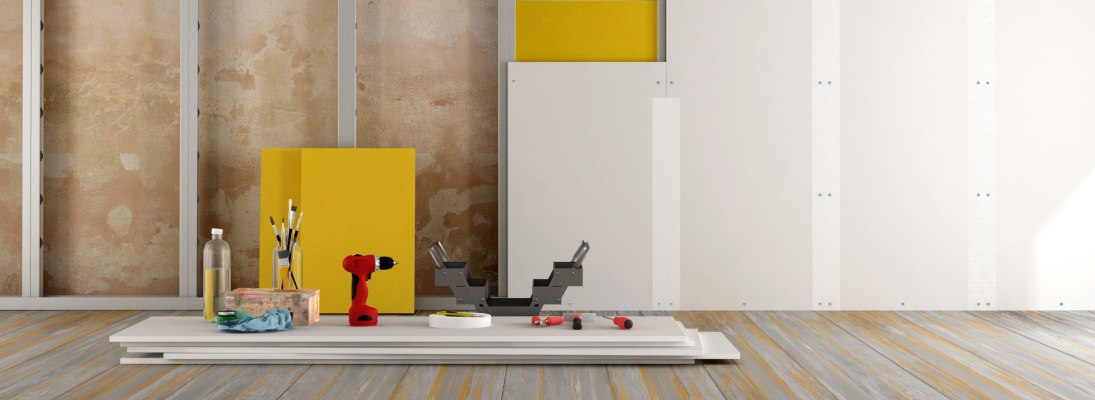 Construction worker assemble a suspended ceiling with drywall and fixing the drywall to the ceiling metal frame with screwdriver. Renovation, construction and ceiling installation concept.