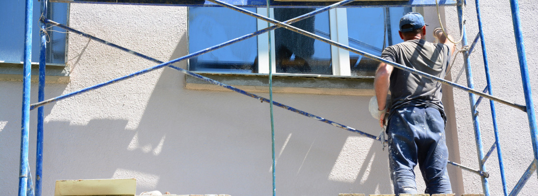 Construction worker assemble a suspended ceiling with drywall and fixing the drywall to the ceiling metal frame with screwdriver. Renovation, construction and ceiling installation concept.