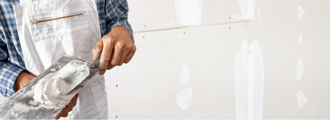 Construction worker assemble a suspended ceiling with drywall and fixing the drywall to the ceiling metal frame with screwdriver. Renovation, construction and ceiling installation concept.