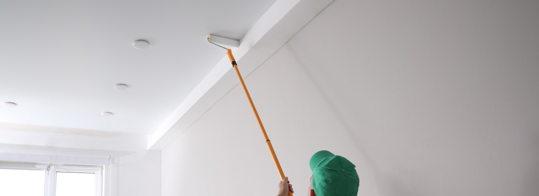 Construction worker assemble a suspended ceiling with drywall and fixing the drywall to the ceiling metal frame with screwdriver. Renovation, construction and ceiling installation concept.