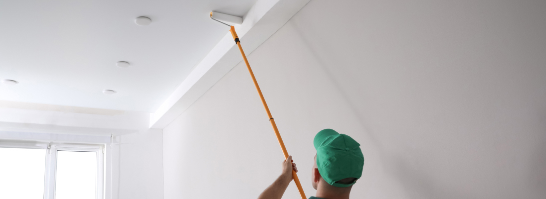 Construction worker assemble a suspended ceiling with drywall and fixing the drywall to the ceiling metal frame with screwdriver. Renovation, construction and ceiling installation concept.