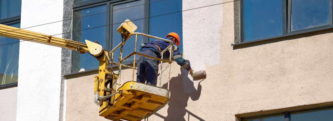 Construction worker assemble a suspended ceiling with drywall and fixing the drywall to the ceiling metal frame with screwdriver. Renovation, construction and ceiling installation concept.