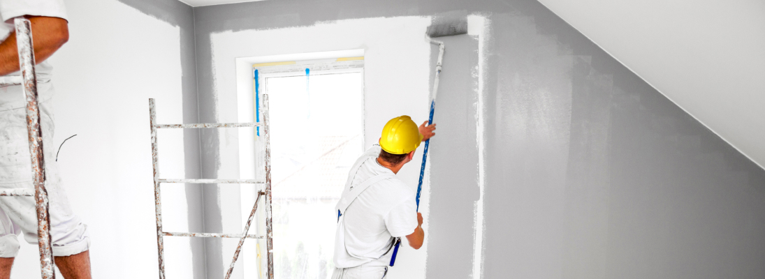 Construction worker assemble a suspended ceiling with drywall and fixing the drywall to the ceiling metal frame with screwdriver. Renovation, construction and ceiling installation concept.