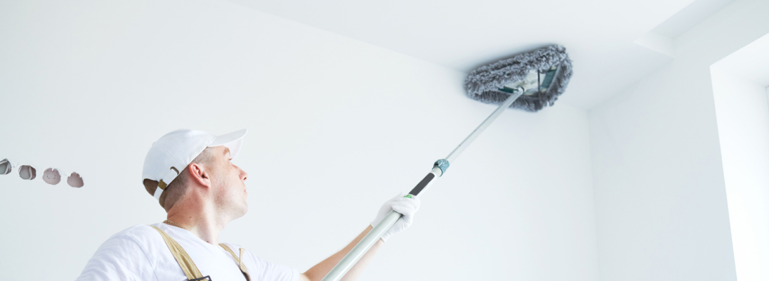 Construction worker assemble a suspended ceiling with drywall and fixing the drywall to the ceiling metal frame with screwdriver. Renovation, construction and ceiling installation concept.