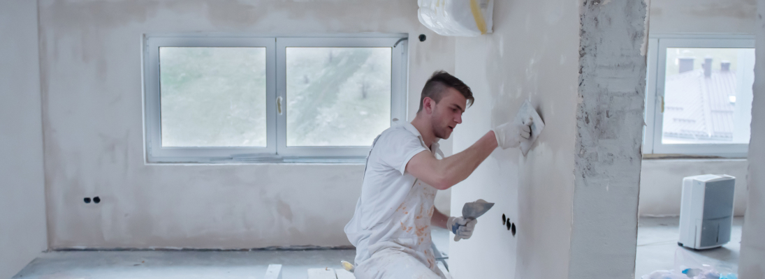 Construction worker assemble a suspended ceiling with drywall and fixing the drywall to the ceiling metal frame with screwdriver. Renovation, construction and ceiling installation concept.