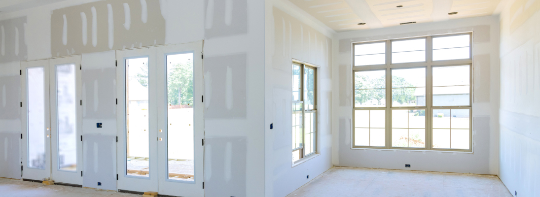 Construction worker assemble a suspended ceiling with drywall and fixing the drywall to the ceiling metal frame with screwdriver. Renovation, construction and ceiling installation concept.