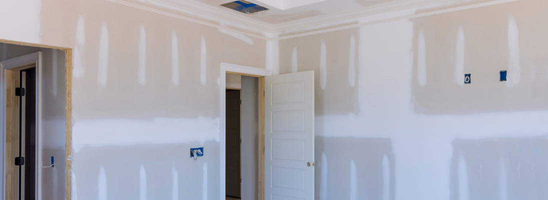 Construction worker assemble a suspended ceiling with drywall and fixing the drywall to the ceiling metal frame with screwdriver. Renovation, construction and ceiling installation concept.