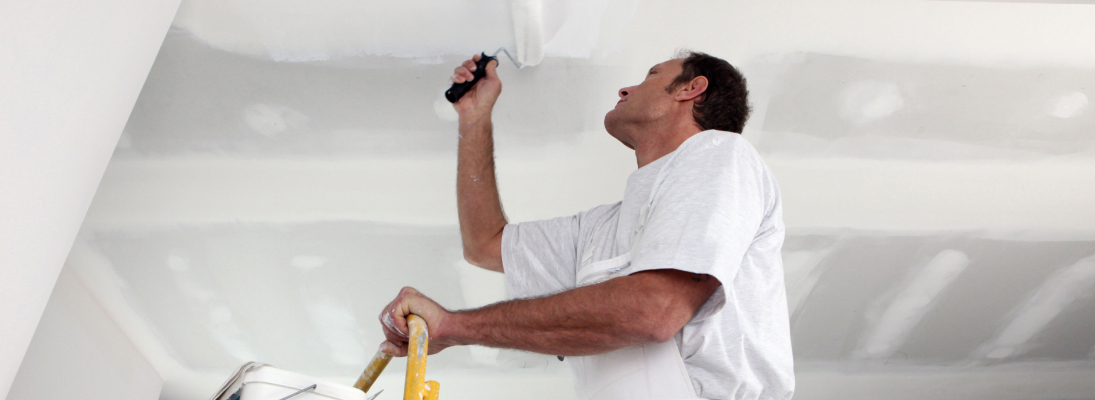 Construction worker assemble a suspended ceiling with drywall and fixing the drywall to the ceiling metal frame with screwdriver. Renovation, construction and ceiling installation concept.