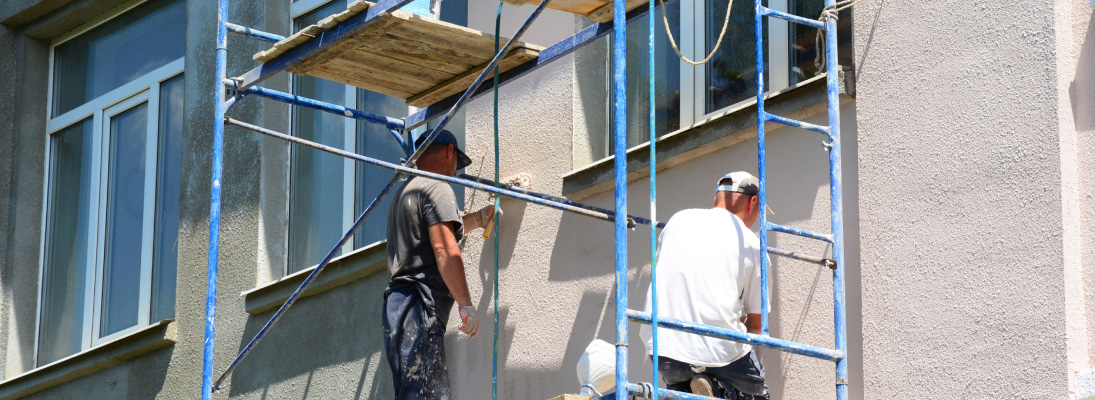 Construction worker assemble a suspended ceiling with drywall and fixing the drywall to the ceiling metal frame with screwdriver. Renovation, construction and ceiling installation concept.