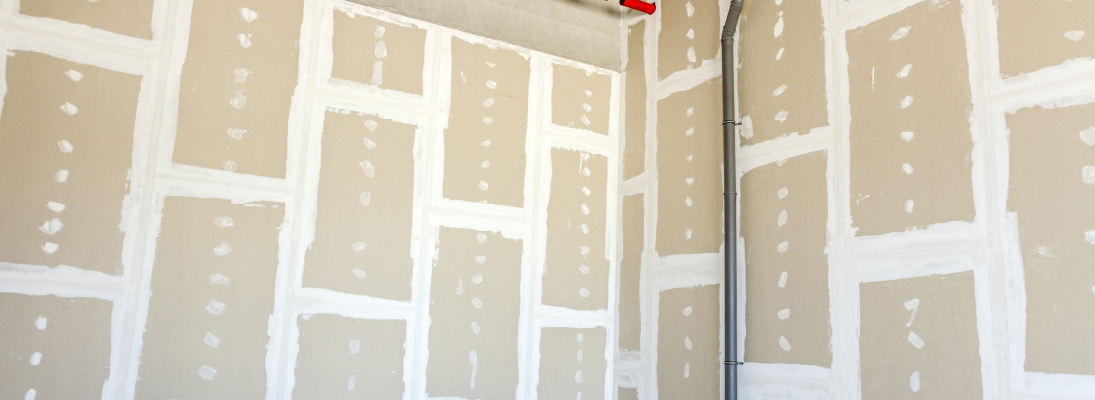 Construction worker assemble a suspended ceiling with drywall and fixing the drywall to the ceiling metal frame with screwdriver. Renovation, construction and ceiling installation concept.